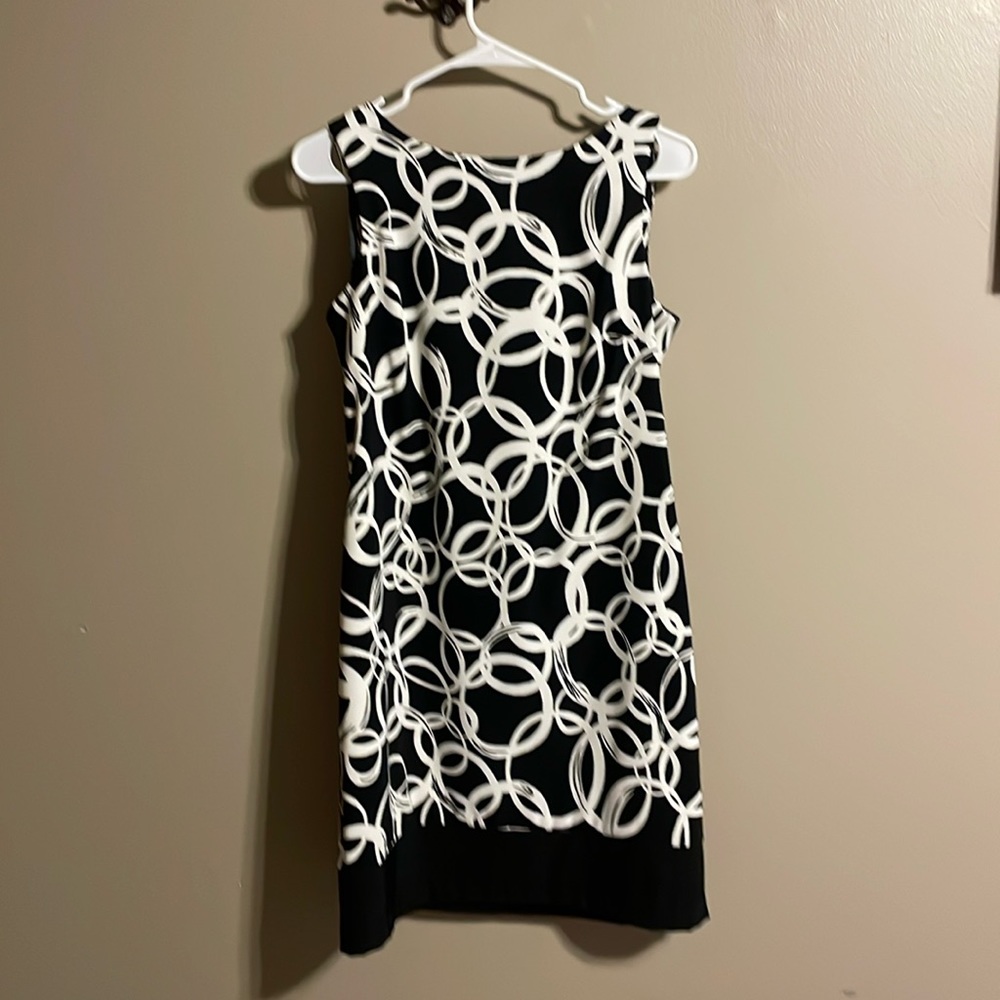 Sleeveless black and white dress with black trim around hemline darted back